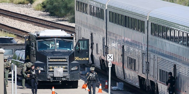 A Tucson Police Department SWAT truck is parked near the last two cars of an Amtrak train in downtown Tucson, Ariz., on Monday. One person is in custody after someone opened fire Monday aboard an Amtrak train parked at the station in the city's downtown. (Mamta Popat/Arizona Daily Star via AP)