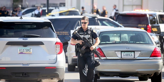 A Tucson Police Department officer walks with his weapon near the scene of a shooting aboard an Amtrak train in downtown Tucson, Ariz., on Monday where a DEA agent and suspect were left dead. (Mamta Popat/Arizona Daily Star via AP)