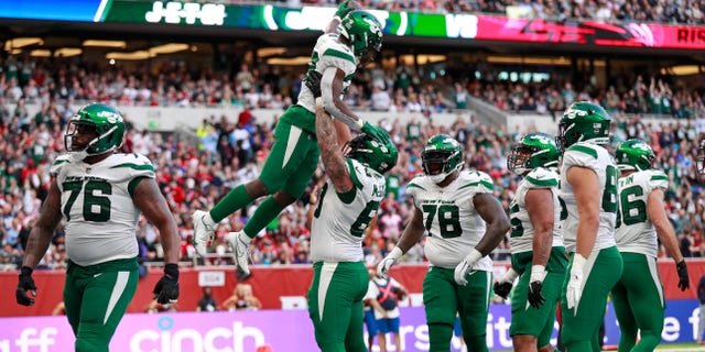 New York Jets running back Michael Carter (32), top center, celebrates after scoring a touchdown during the second half of an NFL football game between the New York Jets and the Atlanta Falcons at the Tottenham Hotspur stadium in London, England, Sunday, Oct. 10, 2021.