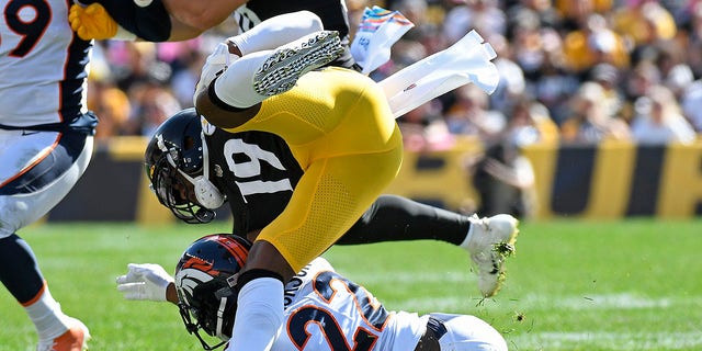 Pittsburgh Steelers wide receiver JuJu Smith-Schuster (19) is upended by Denver Broncos safety Kareem Jackson (22) during the first half of a game in Pittsburgh Oct. 10, 2021.