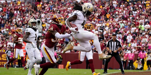 New Orleans Saints running back Alvin Kamara, right, scores a touchdown past Washington soccer team free goaltender Kamren Curl in the first half of an NFL football game on Sunday October 10, 2021, in Landover, Maryland.