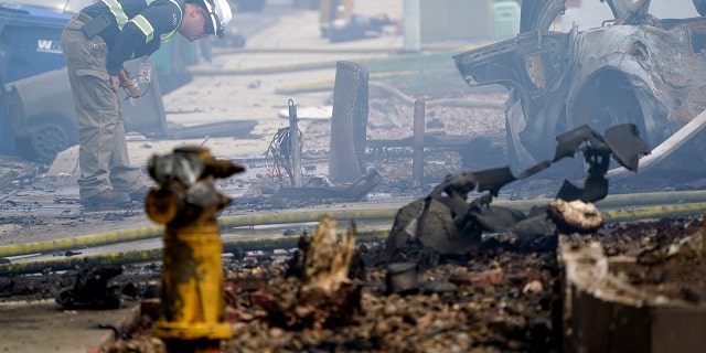 A fire official looks over the scene of a small plane crash, Monday, Oct. 11, 2021, in Santee, Calif. At least two people were killed and two others were injured when the plane crashed into a suburban Southern California neighborhood, setting two homes ablaze, authorities said. (AP Photo/Gregory Bull)