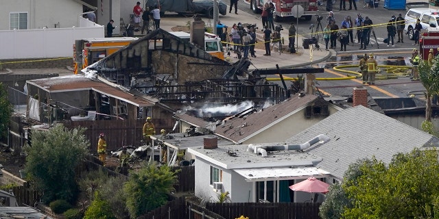 Emergency personnel work at the scene of a small plane crash, Monday, October 11, 2021, in Santee, California, in which two people were killed.  Cody and Courtney Campbell lost their home in the crash. 