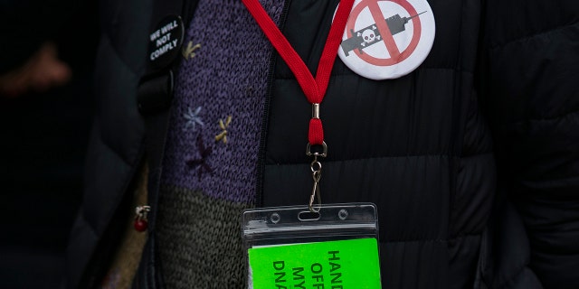 A woman wears an anti-vaccine pin as people and teachers pray as they protest COVID-19 vaccination warrants in Manhattan Federal Court on Tuesday, October 12, 2021, in New York City.