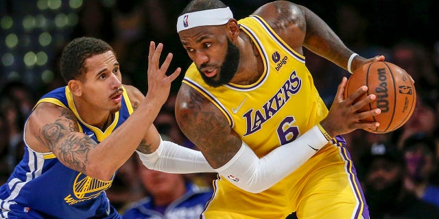 Los Angeles Lakers forward LeBron James, right, is defended by Golden State Warriors forward Juan Toscano-Anderson during the second half of a preseason game in Los Angeles Oct. 12, 2021.