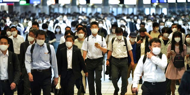 DOSSIER – Dans cette photo d'archive du 1er octobre 2021, des navetteurs portant des masques faciaux pour aider à freiner la propagation du coronavirus marchent dans un passage aux heures de pointe à la gare de Shinagawa, à Tokyo. Presque du jour au lendemain, le Japon est devenu une réussite étonnante et quelque peu mystérieuse de coronavirus. Le nombre de cas est en baisse, mais les experts craignent que, sans savoir exactement comment cela a réduit les cas de manière aussi drastique, la nation pourrait être en réserve pour une autre vague dévastatrice comme pendant l'été. (AP Photo/Eugene Hoshiko, Dossier)