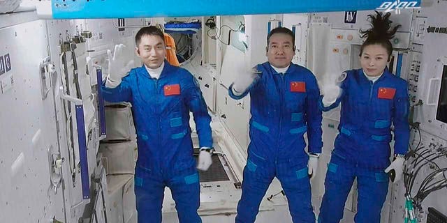 En esta foto publicada por la Agencia de Noticias Xinhua, la imagen de la pantalla tomada en el Centro de Control Aeroespacial de Beijing en Beijing, China, el sábado 16 de octubre de 2021, muestra a tres astronautas chinos, de izquierda a derecha, Yi Guangfu, Zhai Zhigang y Wang Yaping saludando después de ingresar. espacio.  La unidad básica de la estación Tianhe.