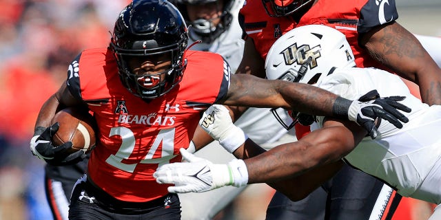 Cincinnati running back Jerome Ford (24) carries the ball as he breaks a tackle against UCF linebacker Jeremiah Jean-Baptiste, right, during the first half of an NCAA college football game, Saturday, Oct. 16, 2021, in Cincinnati. (AP Photo/Aaron Doster)