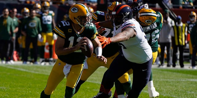 Green Bay Packers quarterback Aaron Rodgers (12) scrambles under pressure from Chicago Bears' Akiem Hicks during the first half of an NFL football game Sunday, Oct. 17, 2021, in Chicago.