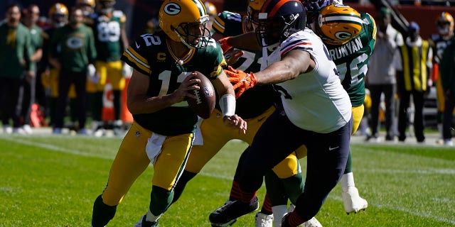 Green Bay Packers quarterback Aaron Rodgers (12) scrambles under pressure from Chicago Bears' Akiem Hicks during the first half of an NFL football game Sunday, Oct. 17, 2021, in Chicago.