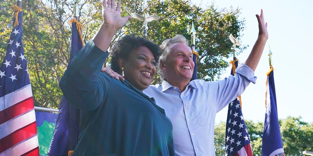 Voting rights activist Stacey Abrams, left, waves to the crowd with Democratic gubernatorial candidate, former Virginia Gov. Terry McAuliffe, right, during a rally in Norfolk, Va., Sunday, Oct. 17, 2021. Abrams was in town to encourage voters to vote for the Democratic gubernatorial candidate in the November election. (AP Photo/Steve Helber)