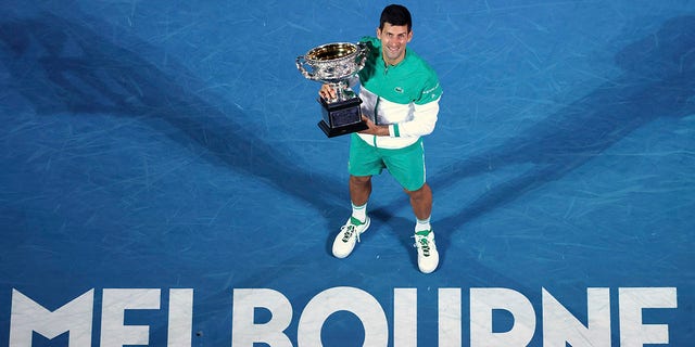 二月. 21, 2021, file photo Serbia's Novak Djokovic holds the Norman Brookes Challenge Cup after defeating Russia's Daniil Medvedev in the men's singles final at the Australian Open tennis championship in Melbourne, 澳大利亚. 