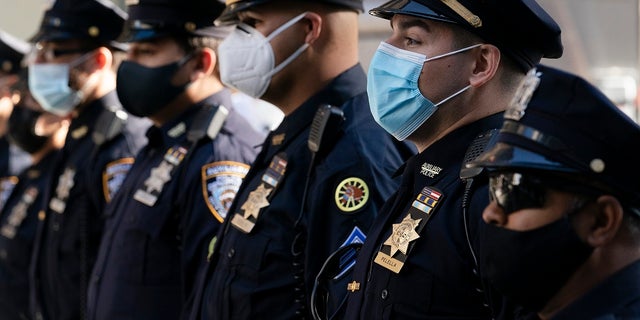 New York Police Department officers in masks stand during a service at St. Patrick's Cathedral in New York to honor 46 colleagues who have died due to COVID-19 related illness. New York City will require police officers, firefighters and other municipal workers to be vaccinated against COVID-19 or be placed on unpaid leave. 