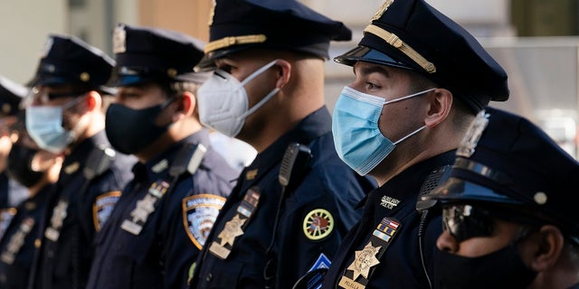 New York Police Department officers in masks stand during a service at St. Patrick's Cathedral in New York to honor 46 colleagues who have died due to COVID-19 related illness. New York City will require police officers, firefighters and other municipal workers to be vaccinated against COVID-19 or be placed on unpaid leave. 