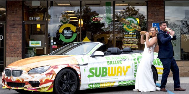 Julie Bushart and Zack Williams posed outside the Subway where they first met each other in 2017 with a Subway-themed convertible sports car and foot-long sandwiches.