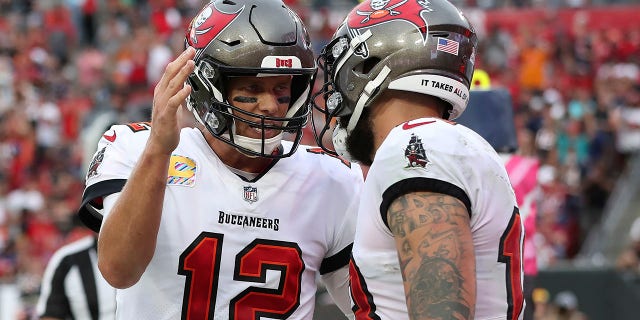 O quarterback do Tampa Bay Buccaneers, Tom Brady (12) comemora com ampla recepção Mike Evans (13) depois que Evans ganhou um passe para touchdown durante a primeira metade de um jogo de futebol americano da NFL contra o Chicago Bears no domingo, 24 de outubro de 2021, em Tampa, Flórida .