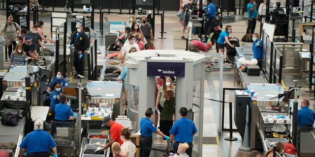 FILE - Travelers wear face coverings in the line for the south security checkpoint in the main terminal of Denver International Airport on Aug. 24, 2021, in Denver. The Biden administration is detailing its new international COVID-19 air travel polices, which will include exemptions for kids and new federal contact tracing requirements. (AP Photo/David Zalubowski)