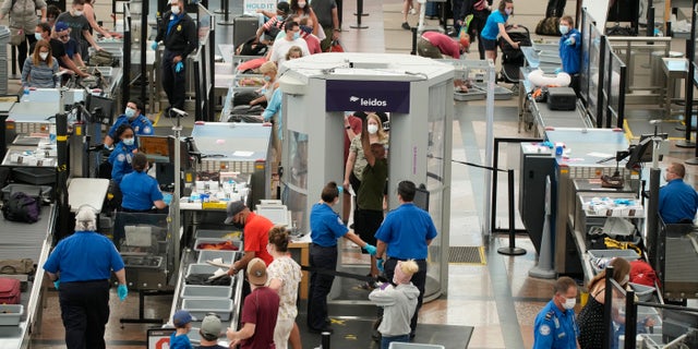 FILE - Travelers wear face coverings in the line for the south security checkpoint in the main terminal of Denver International Airport on Aug. 24, 2021, in Denver. The Biden administration is detailing its new international COVID-19 air travel polices, which will include exemptions for kids and new federal contact tracing requirements. (AP Photo/David Zalubowski)