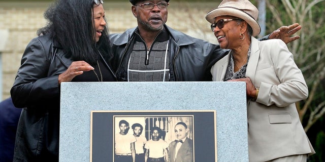 Relatives of the Groveland Four, from left, Vivian Shepherd, niece of Sam Shepherd; Gerald Threat, nephew of Walter Irvin, and Carol Greenlee, daughter of Charles Greenlee, gather at a monument in front of the Old Lake County courthouse in Tavares, Fla., Feb. 21, 2020. (Joe Burbank/Orlando Sentinel via AP)