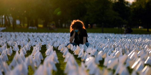 Zoe Nassimoff, of Argentina, looks at white flags that are part of artist Suzanne Brennan Firstenberg's temporary art installation, "In America: Remember," in remembrance of Americans who have died of COVID-19, on the National Mall in Washington, Sept. 17, 2021.