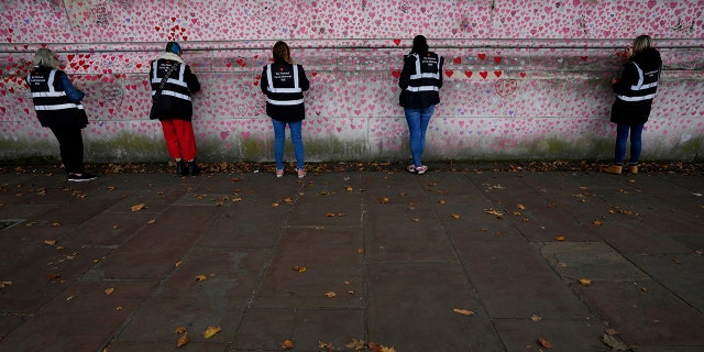 Volunteers work on the COVID-19 memorial wall in Westminster in London, Friday, Oct. 15, 2021. 