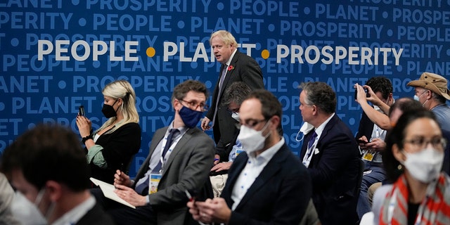 British Prime Minister Boris Johnson walks past a sign reading "People, Planet, Prosperity" as he arrives for a press conference at the La Nuvola conference center for the G20 summit in Rome, Sunday, Oct. 31, 2021. Leaders of the world's biggest economies made a compromise commitment Sunday to reach carbon neutrality "by or around mid-century" as they wrapped up a two-day summit that was laying the groundwork for the U.N. climate conference in Glasgow, Scotland. (AP Photo/Kirsty Wigglesworth)