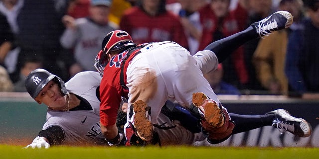 New York Yankees Aaron Judge (99) is tagged at the plate by Boston Red Sox wide receiver Kevin Plawecki as he tries to score on a Giancarlo Stanton single in the sixth inning of a playoff baseball game of the American League Wild Card at Fenway Park, Tuesday, October 5, 2021, in Boston.