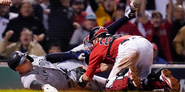 New York Yankees' Aaron Judge is tagged at the plate by Boston Red Sox wide receiver Kevin Plawecki as he tries to score on a single by Giancarlo Stanton in the sixth inning of an American League playoff baseball game Wild Card at Fenway Park, Tuesday, October 5, 2021, in Boston.