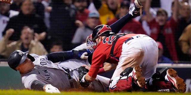 New York Yankees' Aaron Judge is tagged out at the plate by Boston Red Sox catcher Kevin Plawecki as he tries to score on a single by Giancarlo Stanton in the sixth inning of an American League Wild Card playoff baseball game at Fenway Park, Tuesday, Oct. 5, 2021, in Boston.