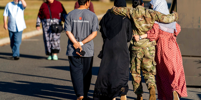 FILE: A female member of the military puts her arms around two female Afghan refugees after they spoke with Secretary of Defense Lloyd Austin as he visits an Afghan refugee camp on Joint Base McGuire Dix Lakehurst, N.J.