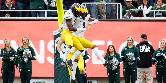 Michigan's Andrel Anthony, right, and A.J. Henning (3) celebrate Anthony's touchdown reception during the first quarter of a game against Michigan State, Saturday, Oct. 30, 2021, in East Lansing, Mich.
