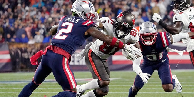 Tampa Bay Buccaneers wide receiver Antonio Brown (81) tries to evade New England Patriots cornerback Jalen Mills (2) during the first half of an NFL football game on Sunday, October 3 2021, in Foxborough, Massachusetts.