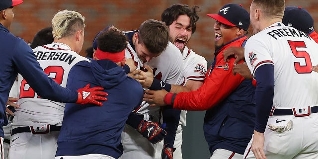 Austin Riley #27 of the Atlanta Braves celebrates with teammates after hitting a walk-off RBI single off Blake Treinen #49 of the Los Angeles Dodgers during the ninth inning of Game One of the National League Championship Series at Truist Park on October 16, 2021 in Atlanta, Georgia.