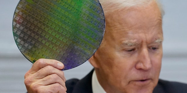 President Joe Biden holds up a silicon wafer as he participates virtually in the CEO Summit on Semiconductor and Supply Chain Resilience in the Roosevelt Room of the White House, Monday, April 12, 2021, in Washington. (AP Photo/Patrick Semansky)