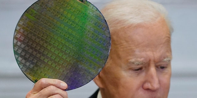 President Joe Biden holds up a silicon wafer as he participates virtually in the CEO Summit on Semiconductor and Supply Chain Resilience in the Roosevelt Room of the White House, Monday, April 12, 2021, in Washington. (AP Photo/Patrick Semansky)