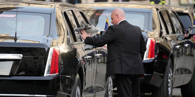 A driver polishes a window of a car in the motorcade of U.S. President Joe Biden as he waits outside the Chigi Palace in Rome, Friday, Oct. 29, 2021. A Group of 20 summit scheduled for this weekend in Rome is the first in-person gathering of leaders of the world's biggest economies since the COVID-19 pandemic started.