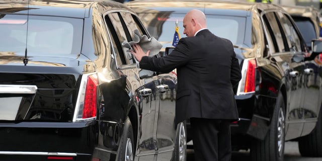 A driver polishes a window of a car in the motorcade of U.S. President Joe Biden as he waits outside the Chigi Palace in Rome, Friday, Oct. 29, 2021. A Group of 20 summit scheduled for this weekend in Rome is the first in-person gathering of leaders of the world's biggest economies since the COVID-19 pandemic started.