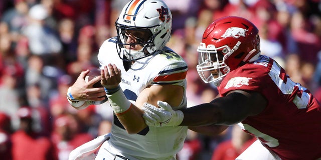 Auburn quarterback Bo Nix (10) slips past Arkansas defensive lineman Eric Gregory (50) as he runs for a touchdown during the second half of an NCAA college football game Saturday, Oct. 16, 2021, in Fayetteville, Ark.