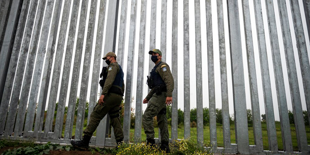 FILE: Police officers patrol alongside a steel wall at Evros river, near the village of Poros, at the Greek-Turkish border, Greece.