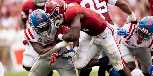 Alabama running back Brian Robinson Jr. (4) runs by Mississippi linebacker Lakia Henry (0) during the first half of an NCAA college football game, Saturday, Oct. 2, 2021, in Tuscaloosa, Ala.