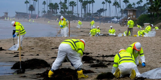 FILE - In this Oct. 7, 2021, file photo, workers in protective suits clean the contaminated beach in Corona Del Mar after an oil spill in Newport Beach, Calif. 