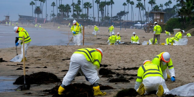 FILE - In this Oct. 7, 2021, file photo, workers in protective suits clean the contaminated beach in Corona Del Mar after an oil spill in Newport Beach, Calif.