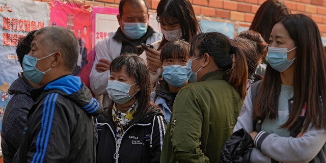 Residents wearing face masks to help curb the spread of the coronavirus gather at a vaccination site as they wait to receive booster shots against COVID-19 in Beijing on Monday.