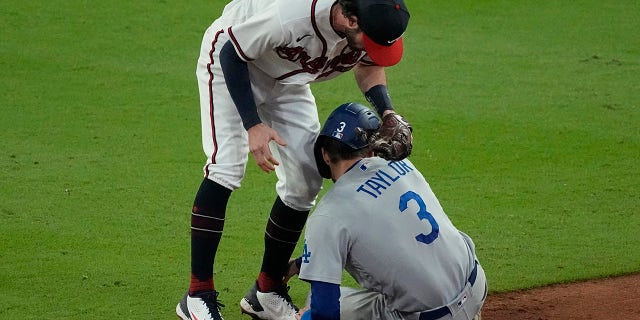 Los Angeles Dodgers' Chris Taylor (3) is tagged out by Atlanta Braves shortstop Dansby Swanson after being caught in a run down on base hit by Dodgers' Cody Bellinger during the ninth inning in Game 1 of baseball's National League Championship Series Saturday, Oct. 16, 2021, in Atlanta.