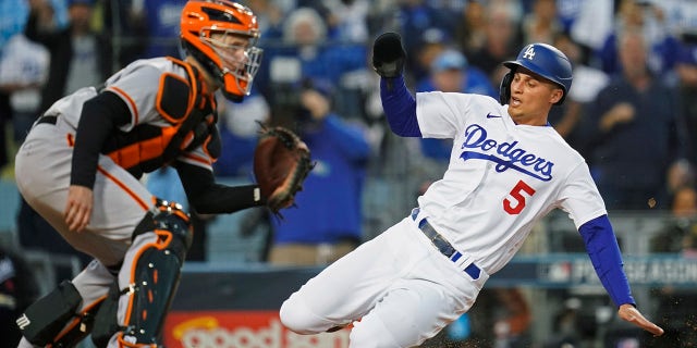 Los Angeles Dodgers' Corey Seager scores on a double by Trea Turner, ahead of the throw to San Francisco Giants catcher Buster Posey during the first inning of Game 4 of a baseball National League Division Series, Tuesday, Oct. 12, 2021, in Los Angeles.