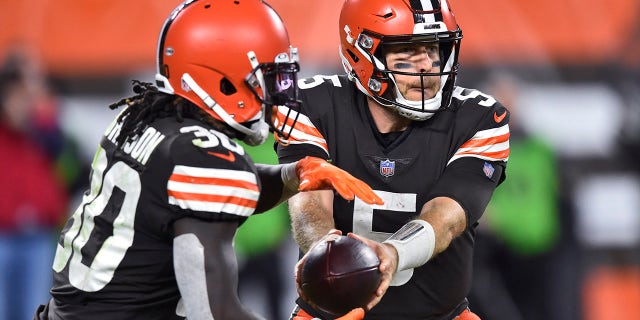 Le quart-arrière des Cleveland Browns Case Keenum (5) remet le ballon au porteur de ballon D'Ernest Johnson (30) au cours de la seconde moitié du match de football de l'équipe de la NFL contre les Broncos de Denver, le jeudi 21 octobre 2021, à Cleveland. 