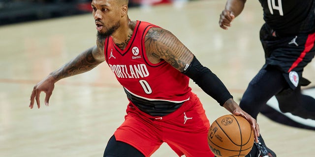 El portero de los Portland Trail Blazers, Damian Lillard, camina hacia la canasta pasando al portero de Los Angeles Clippers, Terance Mann, durante la primera mitad de un juego en Portland, Oregón, el 29 de octubre de 2021.