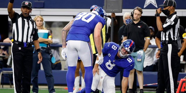 New York Giants tight end Kyle Rudolph (80) checks on quarterback Daniel Jones (8) after Jones was tackled short of the end zone in the first half of an NFL football game against the Dallas Cowboys in Arlington, Texas, Sunday, Oct. 10, 2021. Jones suffered and unknown injury on the play.