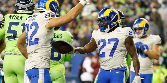 Los Angeles Rams running back Darrell Henderson (27) hands the ball over to tight end Johnny Mundt (82) after Henderson scored a touchdown against the Seattle Seahawks in the second half of a NFL football game on Thursday, October 7, 2021, in Seattle.