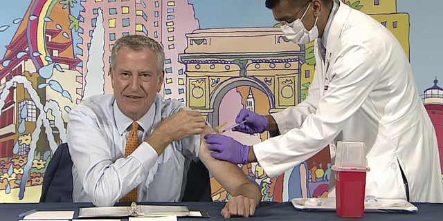 New York Mayor Bill de Blasio, left, receives a COVID-19 Moderna vaccine booster from New York City Health Commissioner Dr. Dave Chokshi during the mayor's daily news briefing on Monday.